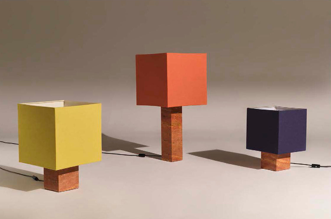 Three colorful red travertine square table lamps on a neutral background with shades in yellow, rust, and navy blue