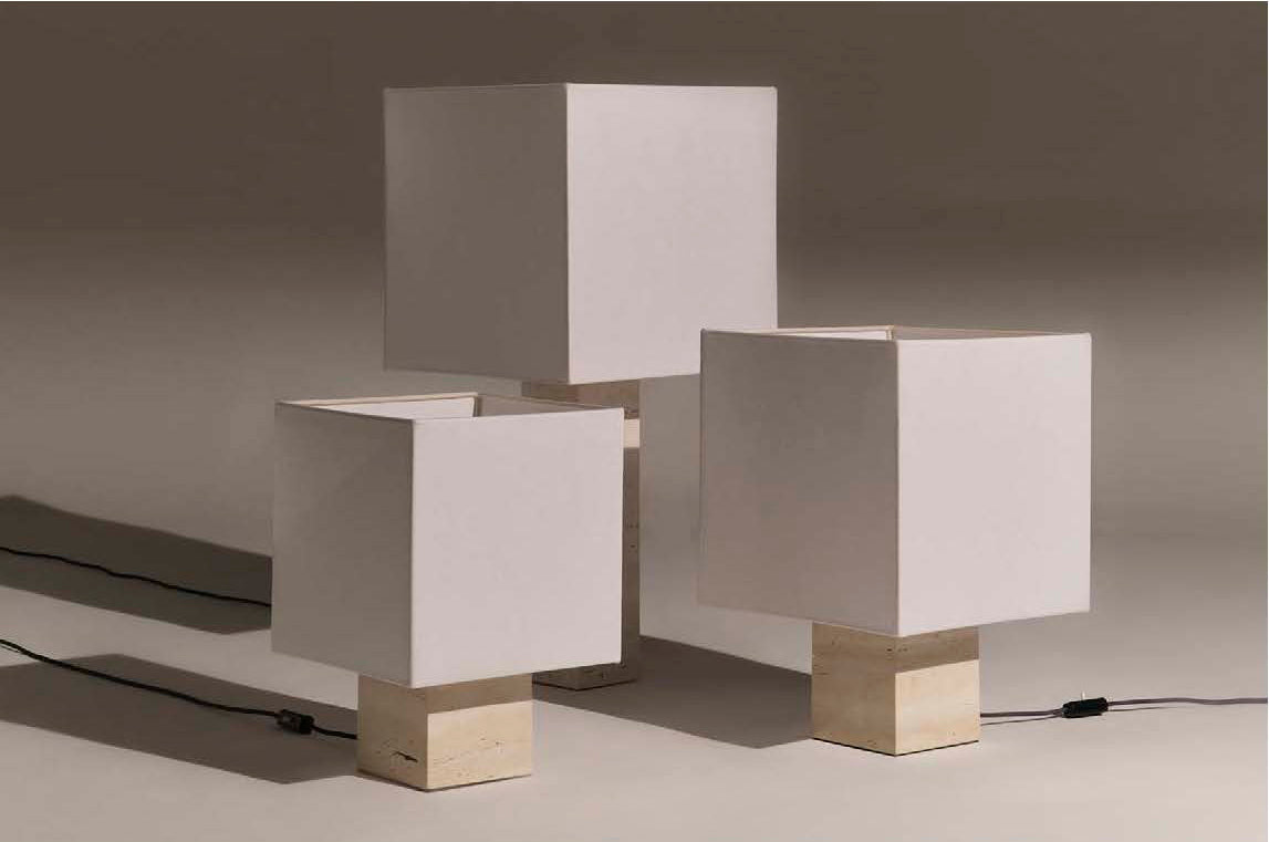 Three white travertine square table lamps in three different sizes on a neutral background 