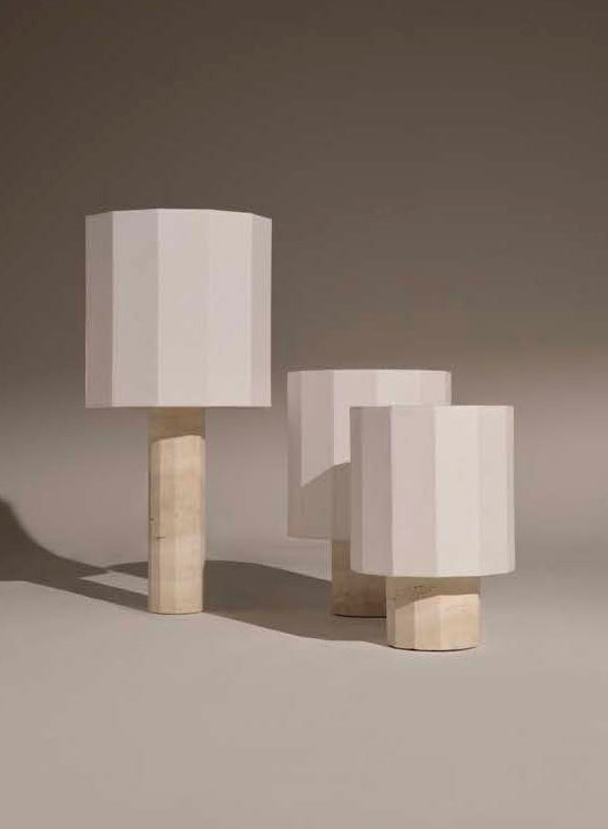 Three white travertine fluted dodecagon table lamps in three different sizes on a neutral background 
