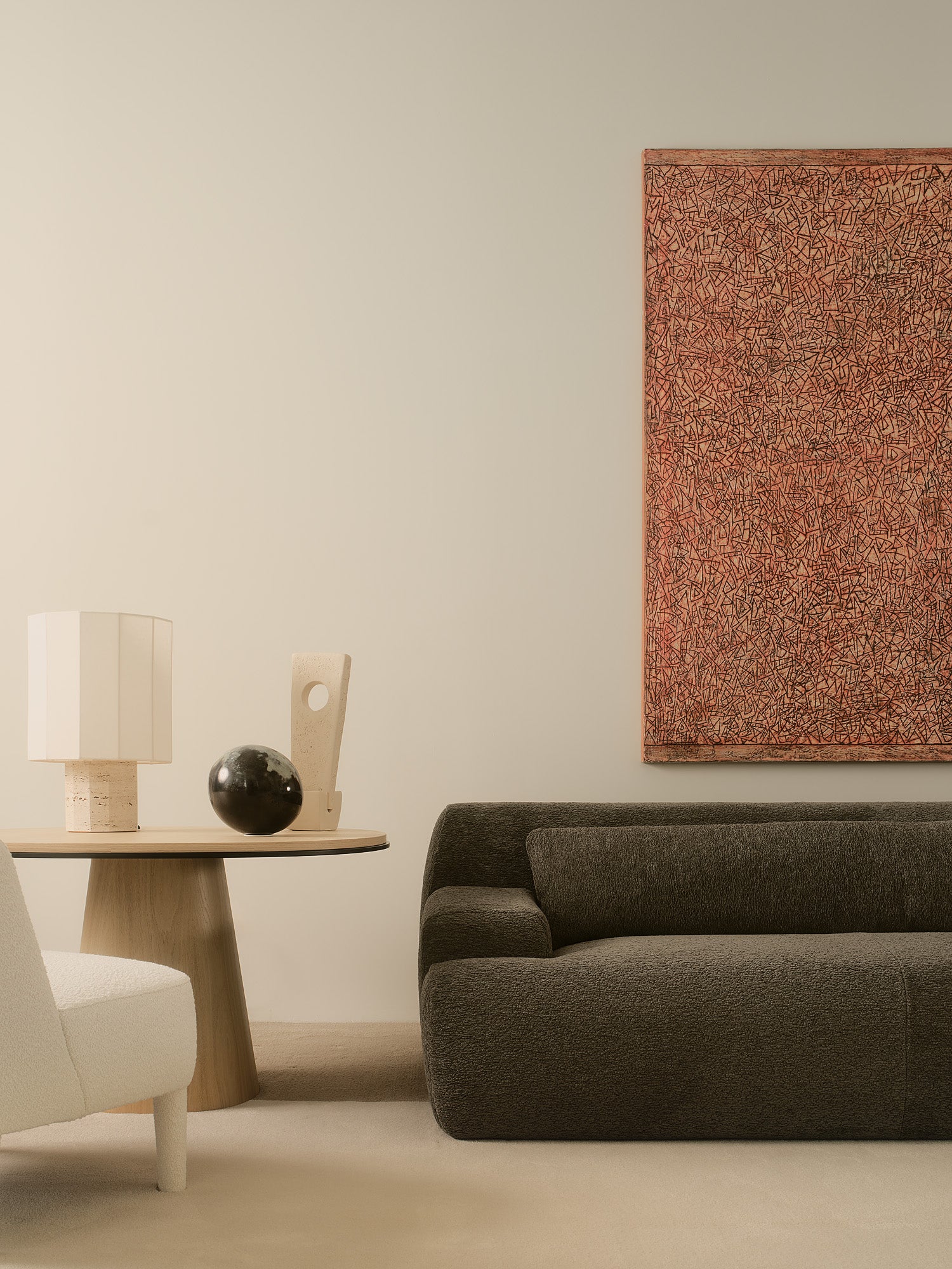 Modern living room with a gray sofa, white travertine lamp on side table, and abstract painting.