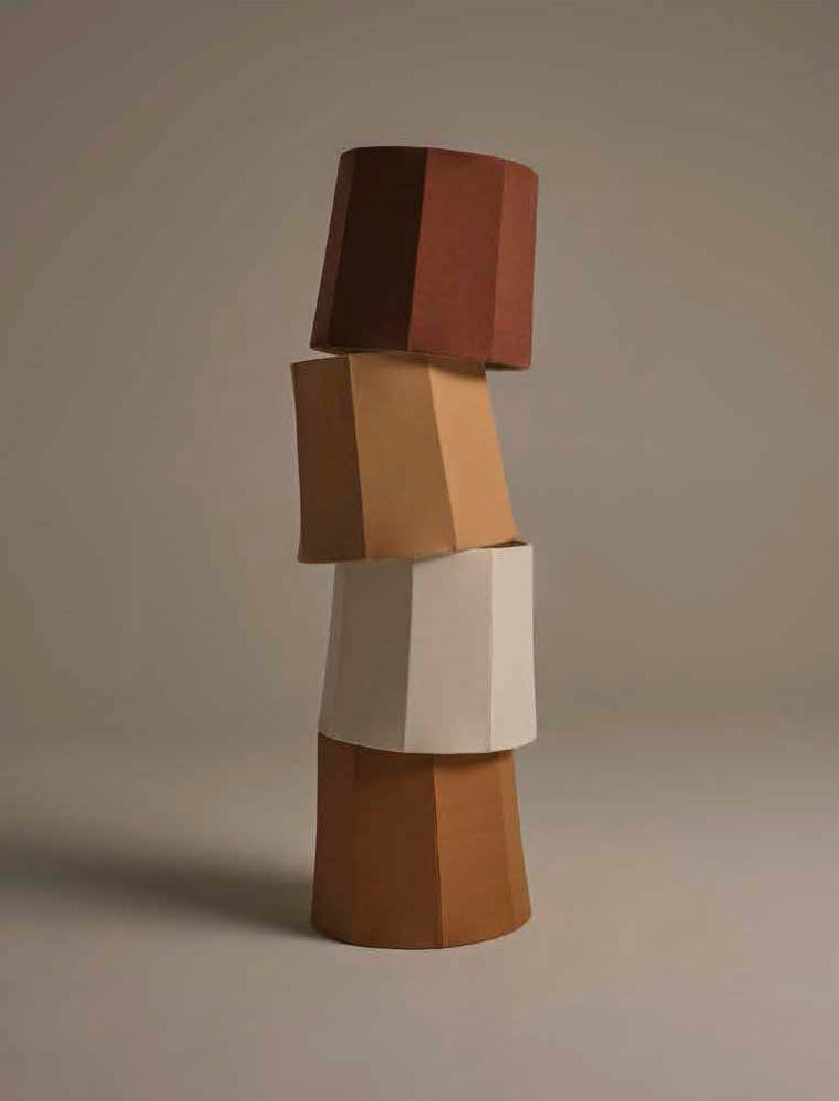 A stack of four handmade linen lamp shades pictured in chocolate, sand, white, and caramel from top to bottom on a neutral background
