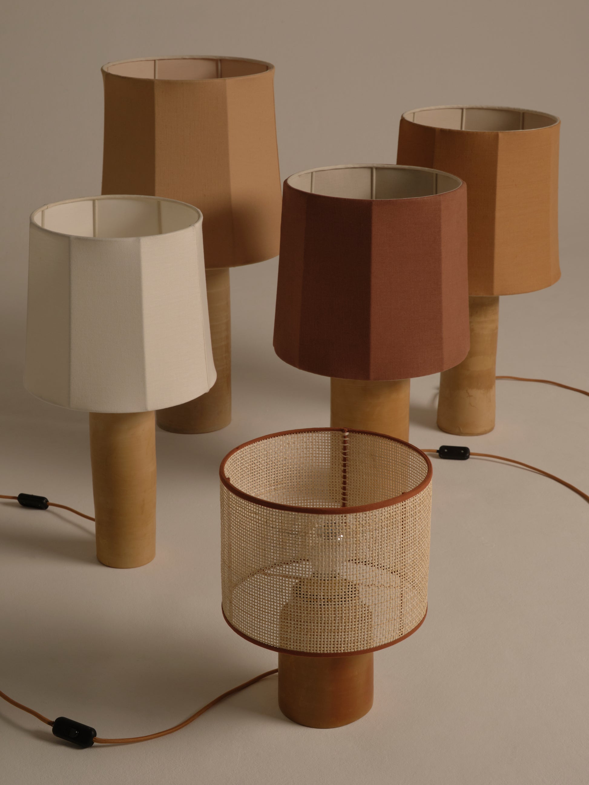 Set of five table lamps with different colored lampshades on a neutral background
